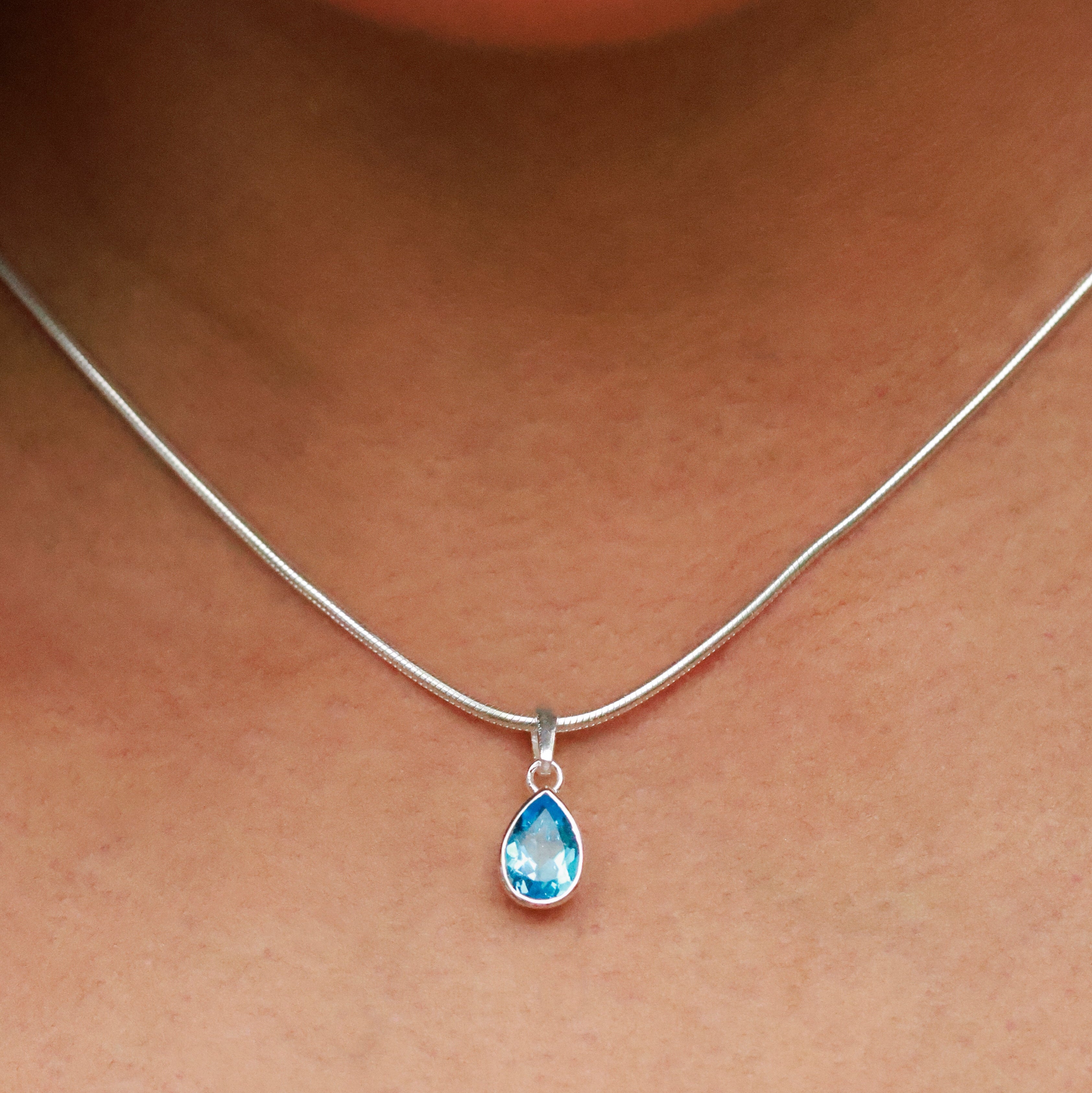 Necklace with a blue teardrop pendant worn by a person